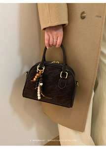 Detail of vintage brown pillow bag with gold ring hardware and beaded charm accessory