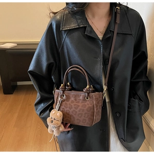 Secchiello chic leopardato con ciondolo a orsetto abbinato a cappotto di pelle nera