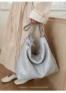 Detail of woven light grey tote bag with silver star charm and minimalist retro design