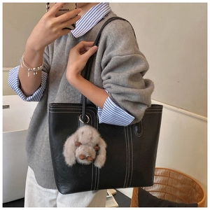 Detail der schwarzen Shopper-Tasche mit Kontrastnähten und Plüsch-Hasen-Anhänger