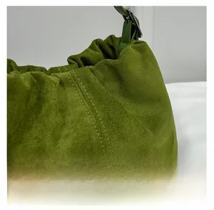 Close-up of green pleated bucket bag showing suede texture and adjustable strap buckle