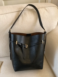 Secchiello classico in pelle nera con dettagli dorati su un divano beige
