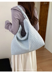 Detailed texture of light blue woven leather tote bag with silver buckle on strap