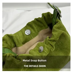 Detail showing silver magnetic buckles and green suede texture of the bucket bag