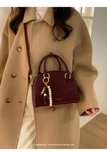 Close-up of retro burgundy leather bowling bag with vintage bead charm and gold hardware