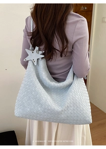 Model view of a light blue woven tote bag with a matching star charm and hobo style