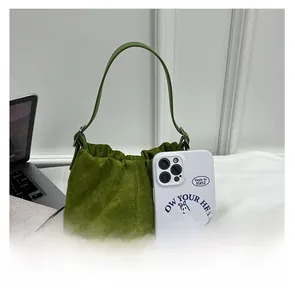 Size comparison of a green pleated bucket bag next to a white smartphone on a desk