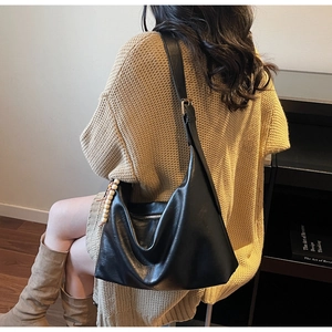 Close-up of a soft black Hobo bag with glossy leather texture and wooden bead charm