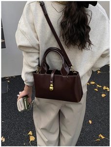 Detail of dark brown leather handbag with golden gourd pendant and adjustable strap