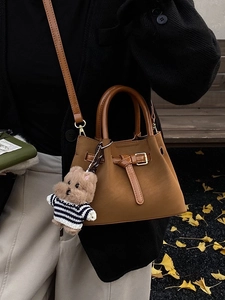 Sac seau chic en daim marron avec pendentif ours dans un décor d'automne