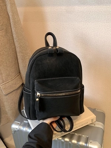Retro black faux suede mini backpack with contrast stitching and gold zippers on luggage
