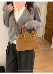 Detail of warm brown matte leather handbag with golden hardware and a retro vibe