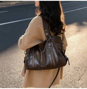 Detail of vintage dark brown tote bag with silver zippers and smooth leather texture