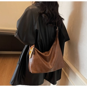 Detail of a brown slouchy hobo tote with ethnic wooden beads and a smooth leather finish