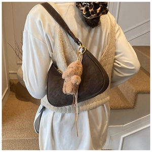 Detail of dark brown faux suede crescent shoulder bag with cute plush animal charm accessory