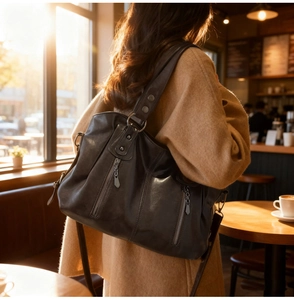 Detail of dark brown leather tote bag with vertical zippers and vintage metal rivets