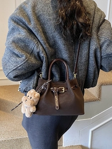 Sac seau vintage en daim marron avec boucle en cuir et breloque peluche sur un modèle