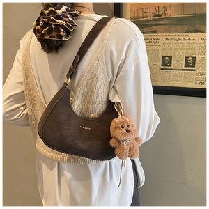 Close-up of a dark coffee leather hobo bag with a cute brown plush bear charm detail