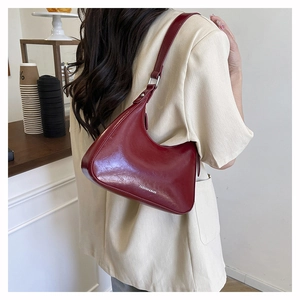 Deep red leather crescent underarm bag with white lettering and silver buckle detail