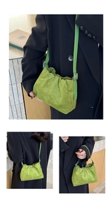 Detail of green pleated suede bucket bag featuring adjustable strap and soft cloud shape