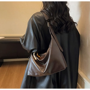 Detail of dark brown leather hobo bag with contrast beaded zipper charm on model