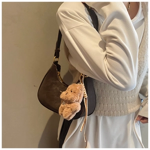 Detail of vintage brown crescent bag with gold zipper and plush puppy charm accessory