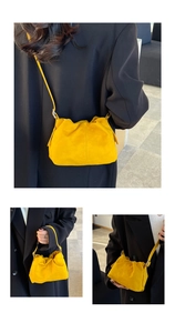 Detail of yellow pleated bucket bag showing soft suede texture and adjustable strap