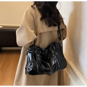 Detail of black glossy PU leather tote bag with silver rings and decorative studs