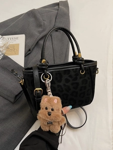 Borsa opaca leopardata con manico a nodo e ciondolo di peluche su giacca grigia
