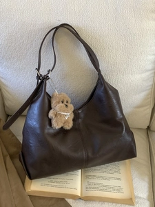 Retro deep brown large tote bag in soft PU leather with cute plush dog pendant on sofa