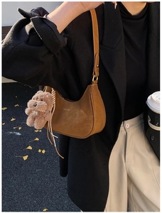 Detail view of a brown vintage hobo bag featuring a plush bear charm and metallic buckle