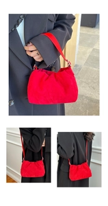 Detail of red pleated suede bucket bag featuring silver metal clips and smooth leather straps