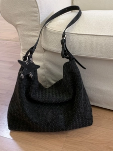 Minimalist black woven hobo bag in suede texture with adjustable strap and star charm