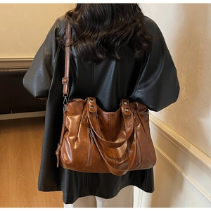 Detail of vintage brown leather tote bag with metallic studs and adjustable shoulder strap