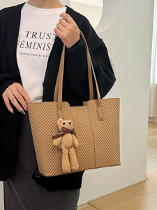 Retro herringbone tote bag with plush bear charm and long leather straps on model
