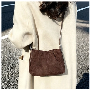 Street style view of a dark brown suede bucket bag with elegant pleated design