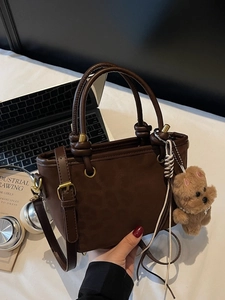 Borsa tote marrone scuro retrò con ciondolo a forma di orso su scrivania da ufficio