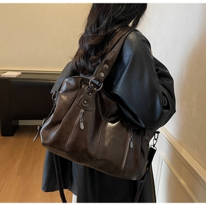 Close-up of side view of a large brown vintage tote bag with decorative zippers