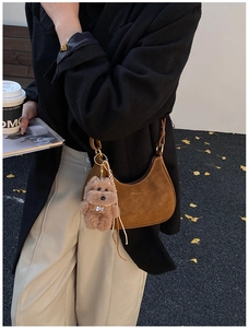 Detailed texture of brown suede saddle bag featuring a cute plush dog charm accessory