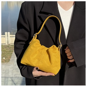 Detailed view of bright yellow pleated cloud bucket bag with textured suede finish