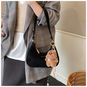 Detail view of black crescent underarm bag with gold hardware and plush bear charm