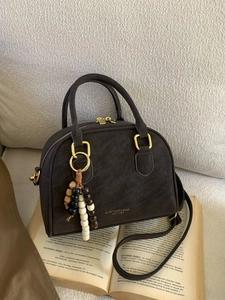 Retro dark brown leather Boston bag with bead charm on an open book background