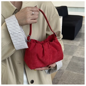 Detail of red pleated suede handbag with silver buckle and matching star ring