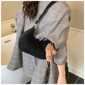 Chic black crescent hobo bag in suede texture with logo detail on a model in a gray suit