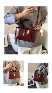 Detailed close-up of glossy wine red bucket bag with gold gourd charm and thin shoulder strap