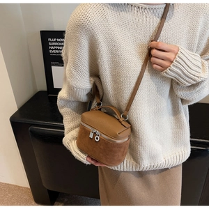 Detailed view of brown suede crossbody bag styled in a modern home interior setting