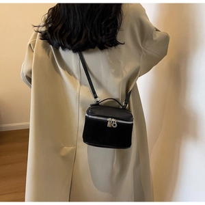 Detail of black crossbody bag with pebble leather and suede texture on khaki trench coat