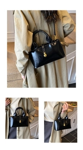 Detail of glossy black bucket bag with gold chain strap and metallic ball charm