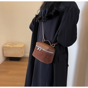 Detail of a brown split-texture crossbody box bag with matte suede and lychee leather