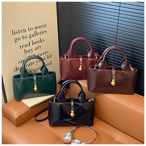 Chic patent leather handbags in four colors displayed on a sofa with gold sphere charms